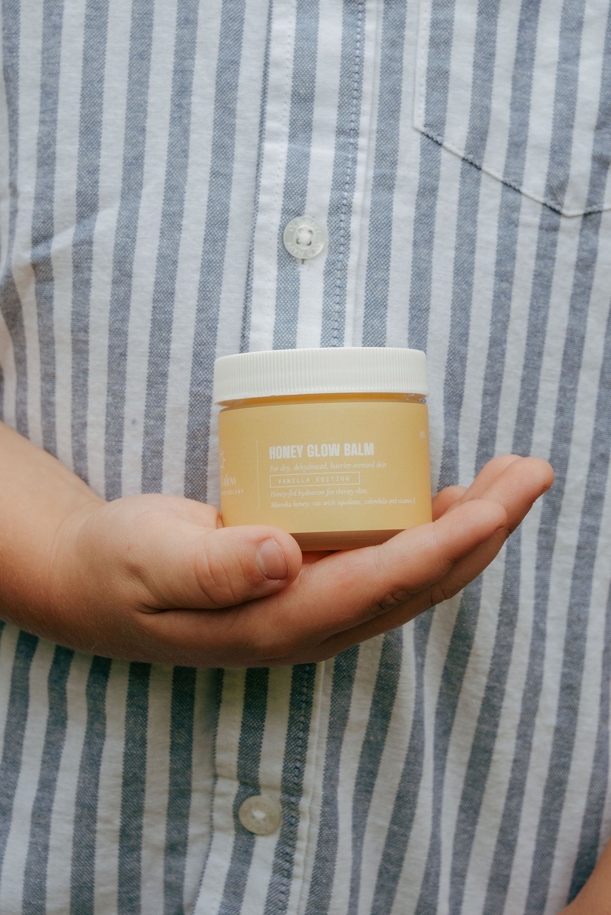 A child’s hands holding a Honey Glow jar