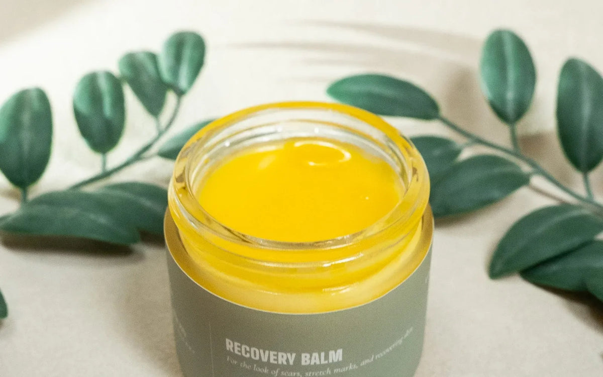 An open jar of Recovery Balm showing the golden whipped texture