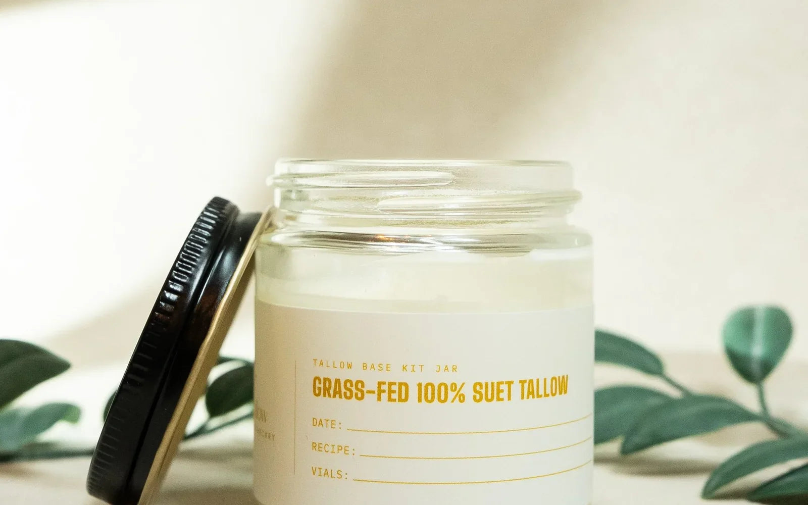 A jar of grass-fed 100% suet tallow with its lid resting beside it
