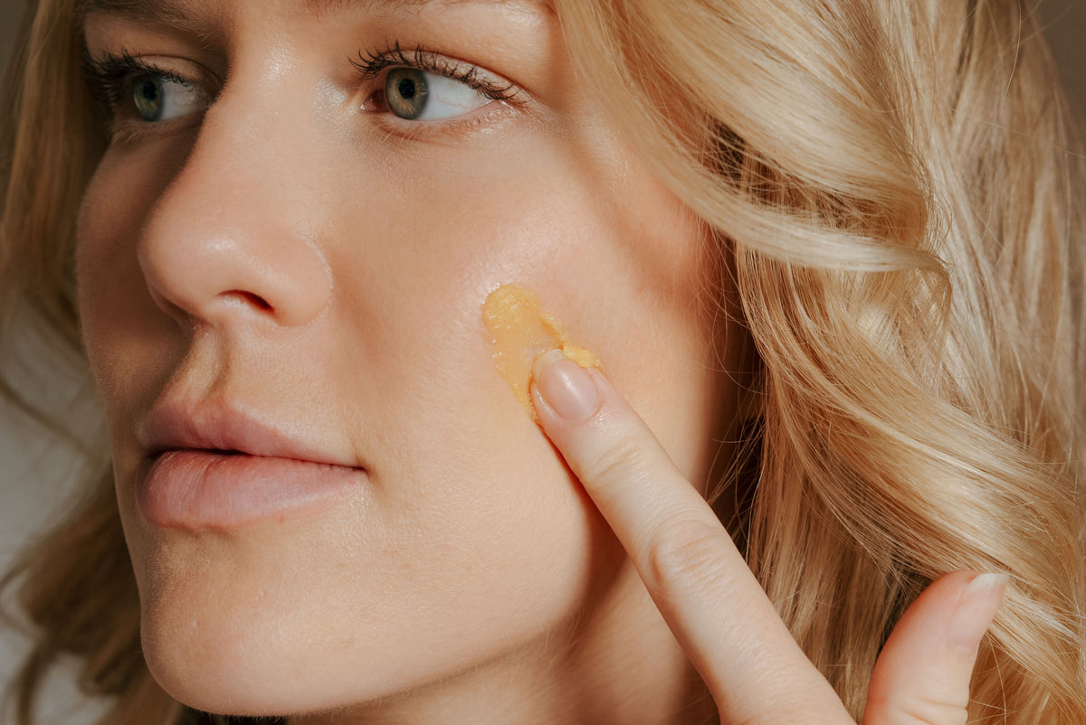 Fingertip pressing a dab of tallow balm onto a cheek in profile